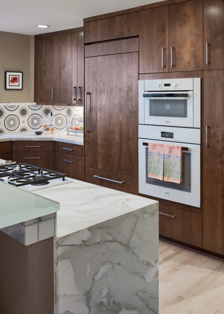 Modern kitchen with wood cabinets and marble island.